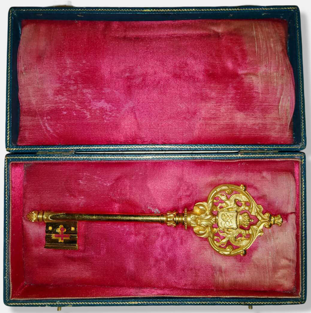 Ein geöffnetes grünes Etui mit roter Seidenauskleidung, das einen badischen Kammerherrenschlüssel enthält (Portepee fehlt).