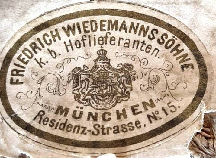 Nahaufnahme eines Klebeschilds der Firma Friedrich Wiedemanns Söhne auf der Rückseite eines Portepees.